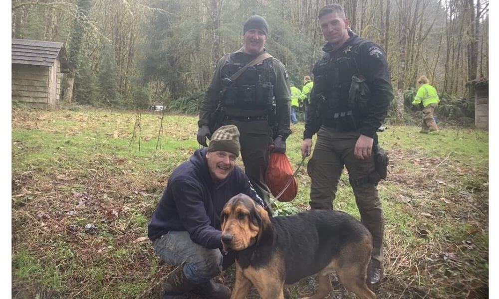 Jamison the bloodhound with his guardian, Nathan, and their two rescuers