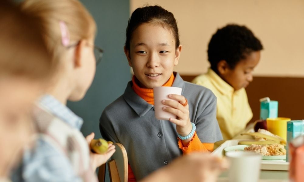 Girl drinking beverage in school cafeteria