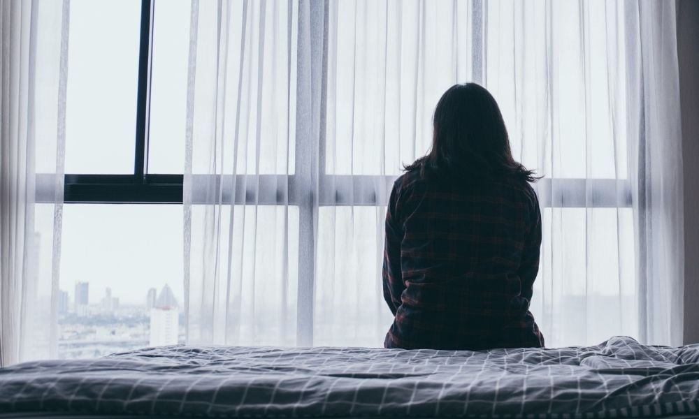 Woman sitting on bed alone