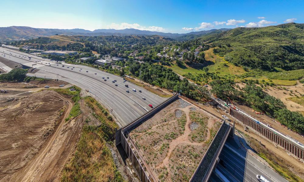 Aerial view of the Wallis Annenberg Wildlife Crossing spanning U.S. 101 and leading toward green hills in Agoura Hills, California.